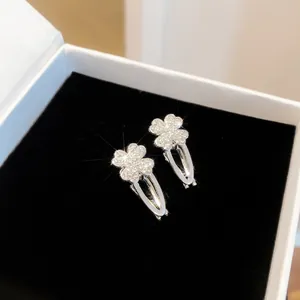 Makroansicht von funkelnden Strass-Vierklee-Haarspangen in einer weißen Schmuckschatulle.