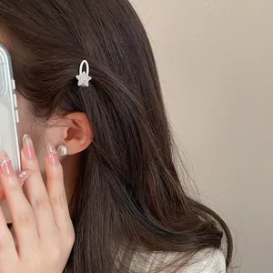 Detailansicht einer silbernen Strass-Stern-Haarspange und quadratischer Perle