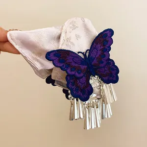 Dettaglio di un fermaglio per capelli a farfalla ricamato viola con nappe argento