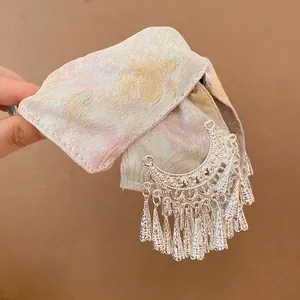 Detailweergave van stoffen haarklem met zilveren kwastjes detail
