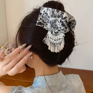Detailweergave van vintage haarklem met paisley-print en zilveren kwastje op model