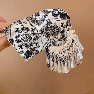 Detailweergave van de paisley stoffen haarklem met zilveren metalen kwastjes detail