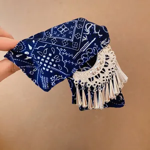 Detailopname van donkerblauwe bedrukte stoffen haarklem met hangende zilveren metalen kwastjes