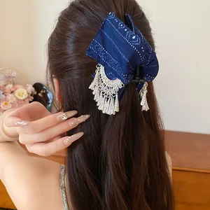 Gedetailleerd achteraanzicht van een blauwe stoffen haarklem met elegante zilveren kwastjes