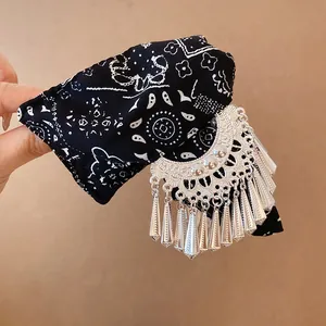 Detail van zwarte haarklem met paisley-print en zilverkleurige kwastjesbedels.