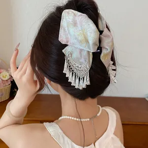 Detailopname van een haarklem met bloemenstrik en zilveren kwastjes op het haar van een vrouw