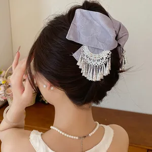 Detailweergave van een paarse stoffen strik haarklem met elegante zilveren kwastjes