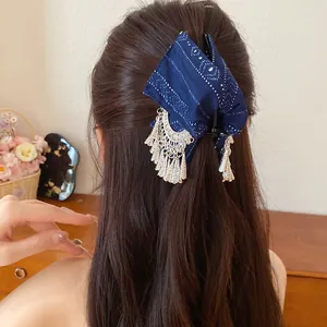 Detail van de donkerblauwe bedrukte haarklem van stof met zilveren kwastjes hangers