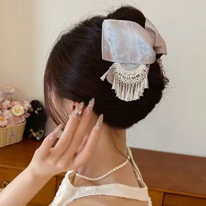 Detail van een vintage haarklem met stoffen strik en zilveren kwastjes