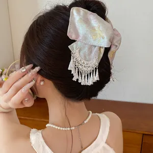 Elegante haarklem met bloemmotief stoffen strik en zilveren kwastje in detail