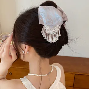 Gedetailleerd overzicht van vintage haarklem met bloemenstrik en elegante metalen kwast.
