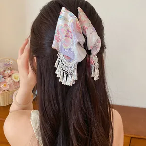 Detailweergave van vintage haarclip met stoffen strik en elegante zilveren kwastjes.