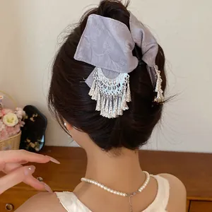Detail van een paarse stoffen strik haarklem met elegante zilveren kwastjes