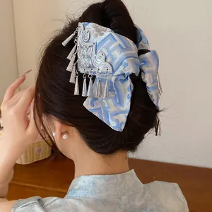 Detailopname van vintage haarklem met blauwe bloemenstof en zilveren kwastjes