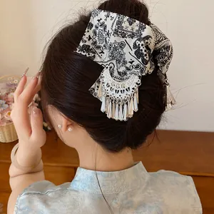 Detailoverzicht van een vintage haarklem met paisley-strik en zilveren kwastjes