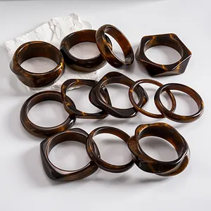 Macro detail of various geometric amber-toned resin bangles with vintage marbled patterns