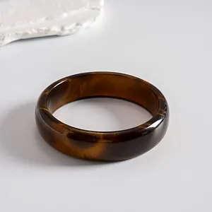 Retro resin bangle bracelet featuring an amber swirl pattern in a minimalist setup
