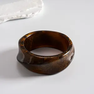 Detailed shot of a vintage marbled resin bangle with geometric brown and gold tones.