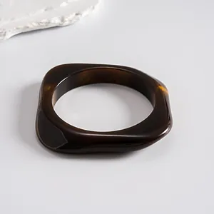 Detailed view of a retro dark amber resin bangle with a geometric square design