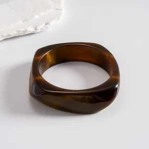 Detailed view of the dark brown swirled resin texture on a geometric square bangle