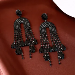 Elegant black rhinestone tassel earrings with water drop crystals on silk background.