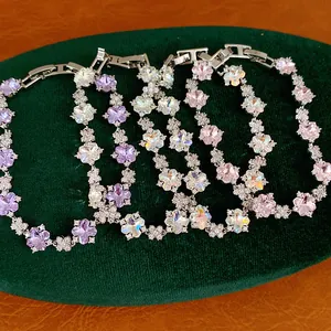 Detailansicht eleganter bunter Zirkon-Blumenarmbänder auf einem grünen Samtdisplay