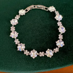Nahaufnahme eines funkelnden Zirkonia-Blumenarmbands mit Kristallen auf dunkelgrünem Samt.