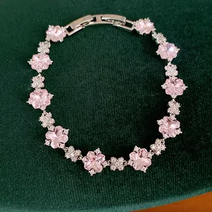 Detaillierte Ansicht eines eleganten rosa Zirkon-Blumenarmbands auf grünem Samthintergrund
