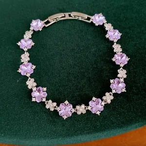 Nahaufnahme eines eleganten Silberarmbands mit lila Zirkonia-Blüten auf Samt