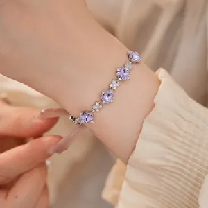 Exquisites Detail eines silbernen Armbands mit lila Zirkon-Kleeblumen am Handgelenk getragen