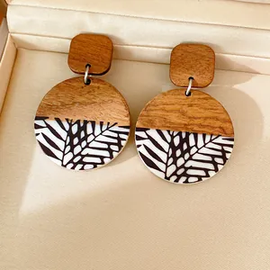 Detail of handmade resin and wood round drop earrings with leaf patterns