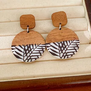 Detailed view of vintage resin and wood round earrings with black leaf pattern