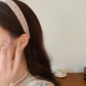 Close-up of a pink acrylic headband with colorful rhinestones on a model
