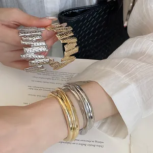 Close-up detail of silver and gold textured metal bangles and smooth stackable rings
