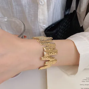 Close-up detail of a minimalist gold textured open cuff bangle bracelet for women