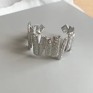 Detailed macro view of silver-tone cuff bracelet with unique hammered geometric texture