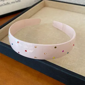Close-up detail of a pink acrylic wide headband with colorful rhinestone accents