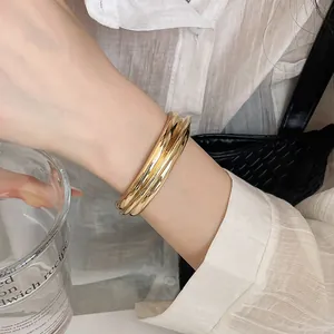 Detail of elegant gold-toned textured open bangle bracelet on model's wrist