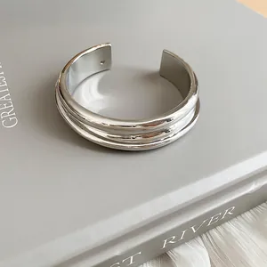 Detail view of a minimalist silver metallic cuff bracelet with elegant layered ribbing.