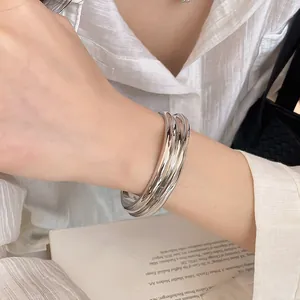 Detail view of a minimalist silver metallic textured open bangle worn on a wrist.