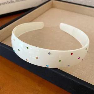 Macro view of cream acrylic headband featuring colorful rhinestone embellishments
