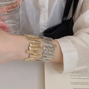 Close-up of irregular hammered texture on gold and silver metal open cuff bracelets