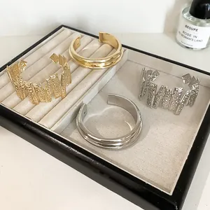 Detail view of gold and silver metal cuff bracelets with smooth and textured finishes