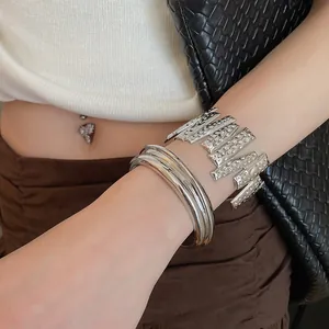 Close-up detail showing the textured silver metal cuff and smooth layered open bangles