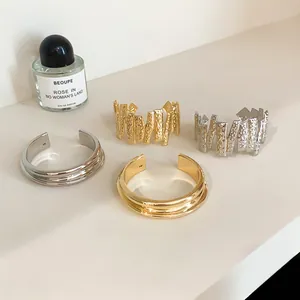 Detail view of gold and silver textured metal open bangles on a minimalist display