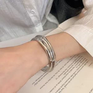 Detailed view of a minimalist silver textured open cuff bracelet worn on the wrist.
