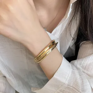 Close-up detail of a minimalist gold layered open cuff bracelet on a female wrist.