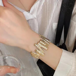 Close-up detail of a textured gold-finish wavy metal cuff bracelet on a wrist