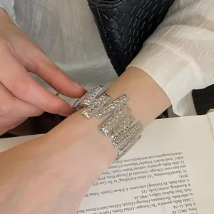 Detail view of a wide textured silver-toned hammered cuff bracelet on a female wrist