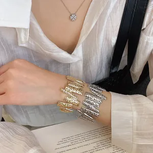 Detailed close-up of gold and silver hammered metal cuff bracelets on a wrist